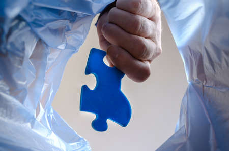 The hand throws the blue puzzle into the trash. A man holds puzzle piece over an trash can. Bottom view. Indoorsの写真素材