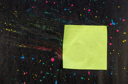 Chaotic drops of paint and piece of paper on black texture. Yellow, red, blue dots and splashes....