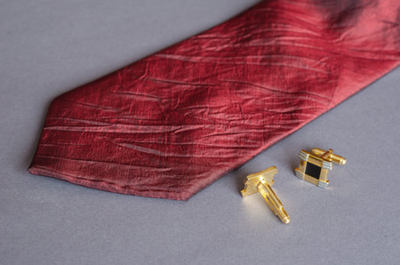 Red tie and yellow cufflinks on gray background. Male Accessories.