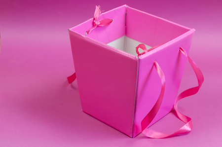Empty pink gift box on a pink background. Cardboard box with tape handles. Minimalism. Selective focus.の写真素材