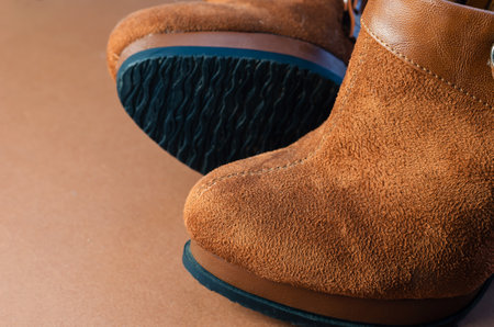 Brown suede women's boots with a thin high heel on a brown background. Fashionable women's shoes made of natural materials.の写真素材