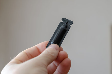 A male hand holds Dog Flea and Tick Drops. Black plastic container with veterinary antiparasitic...