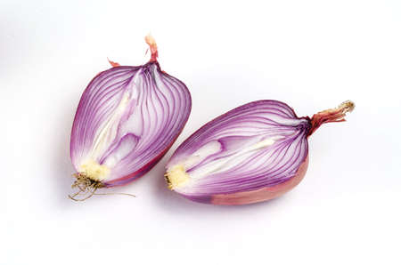 Two halves of a ripe raw unpeeled onion on a white background. Italian Onion Ramata di Milano. Cross section Root vegetable in the peel. Food, ingredients.の写真素材