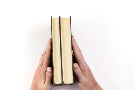 Hands holding green hardcover books on a white background. A man clutches two closed books between his palms. View from aboveの写真素材