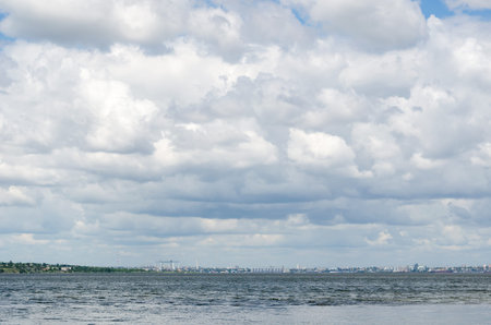 Cloudy sky over the wide river Southern Bug. Solid cloudiness. Seaports, grain elevators and the...