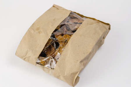 Pet treats in a brown paper bag with a window. Kraft bag with pieces of dried cows udders on a white background. Useful treats for dogs.の写真素材