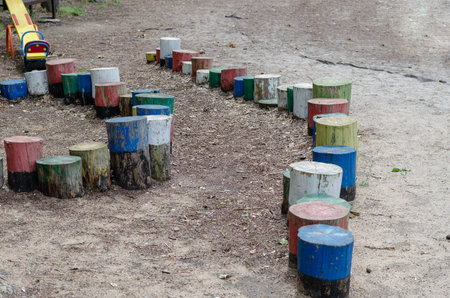 Colorful wooden stumps on the playground. Vertical decorative trunks for balance. Empty playground.
