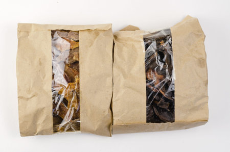 Two packs of dog treats on a white background. Brown paper bags with window. Dried beef kidneys and...