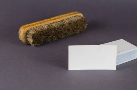 Garment cleaning brush and stack of blank business cards on gray background. Wooden brush with natural bristles and white rectangular business cards. Cleaning services, small business.の写真素材