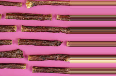 Dog treat sticks on a pink background. Dried beef esophagus. Natural chewy goodies for pets. Stretch pixel effectの写真素材