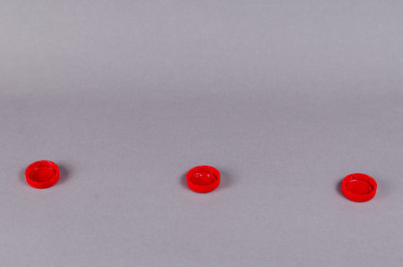 Red bottle stoppers gainsboro background. Minimalist composition with three plastic soft drink...