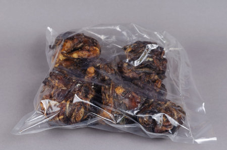 Air dried dog treats on a gray background. Dental treats in transparent packaging. Dried beef...