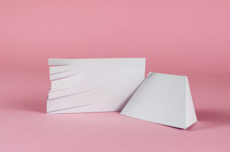 White blank rectangle with cut strips and trapezoid on pink background. Random scissor-cut slip of...