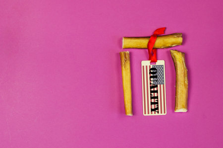 Dog treats and sales tag on pink background. Air dried pet chew sticks. Bully sticks. Beef pizzle....