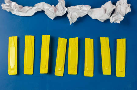 Dog Flea and Tick Drops and scraps of crumpled white paper against blue. Yellow plastic container with veterinary antiparasitic drug for dogs and cats for external use. Pet, Veterinary.の写真素材