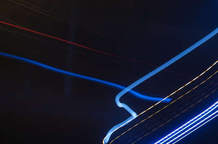Multicolored light traces against dark background. Chaotic lines of the night city. Abstract background. Blurred motion. Defocus. Noise effect.の写真素材