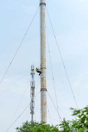 Tall metal pipe and mobile crane against the sky. Preparatory work for install 5g antenna. High-rise worker works in the middle part of the tower. Mykolaiv, Ukraine - 07 05 2021のeditorial素材