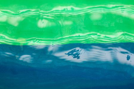 Defocused shot of transparent water against blue and green. Water surface swimming pool with waves...