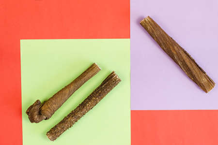 Marketing and advertising of animal products concept. Dog treats on a colorful background. Dried beef stomach sticks. Naturally dried goodies for dogs. Pet. Top view, flat lay.の写真素材
