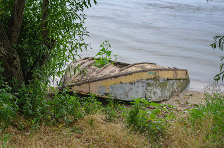 An old ruined wooden boat on the shore. A small fishing boat lies upside down.の写真素材