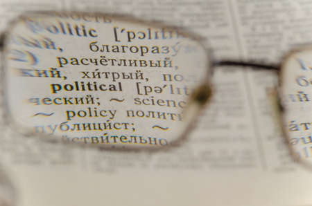 Reading glasses and an open book in close-up. Old Russian-English Dictionary. Selective Focus on the word POLITICAL.の写真素材