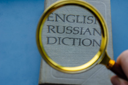 Education, foreign language learning, search for knowledge concept. Magnifying glass and hardcover...