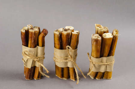 Gray-brown composition with dog treats. Bully sticks wrapped in brown paper and tied with twine. Portioned grouped Beef pizzle.Chewing treats.の写真素材