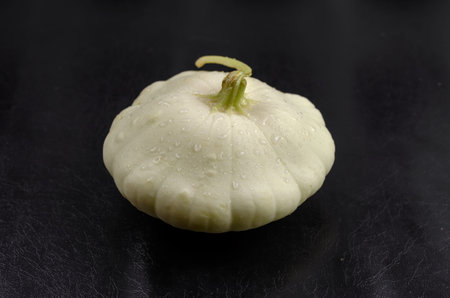 Minimalist composition with one Pattypan squash on the black background. Raw Patty pan with water...