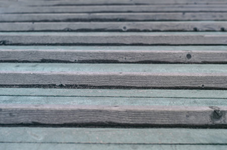 Close-up of repeating wooden laths in distant perspective. Old weathered bars with knots. Selective...