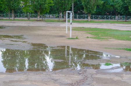 A soccer field with puddles after a downpour. An empty sports field with a white goalpost. Daytime. No people.の写真素材