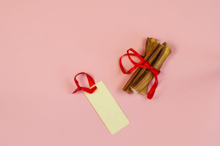 Dog treats and sales tag on pink background. Air dried pet chew sticks. Bully sticks. Beef pizzle....