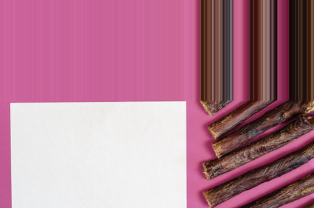 Sticks of dog treats and a blank white sheet on a pink background. Dried beef esophagus. Natural...
