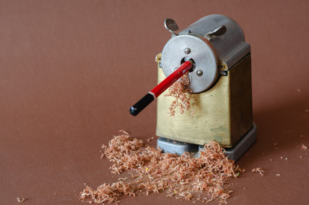 Old sharpener, pencil and shavings on brown background. Vintage stationery. Minimalism. Selective...