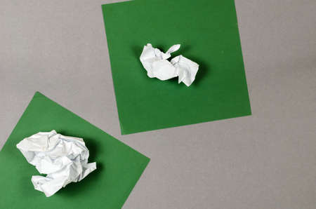 Green squares and white crumpled paper against a gray background. View from above.の写真素材
