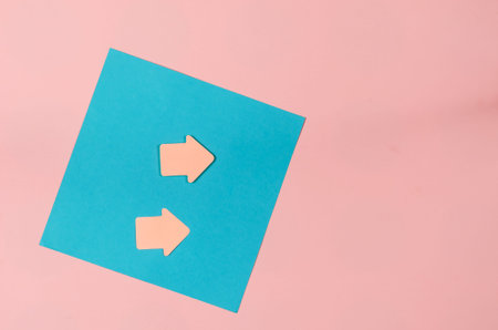 Sheet of paper and bookmark arrows on a pink background. Blue square sheet of paper. Top view.の写真素材