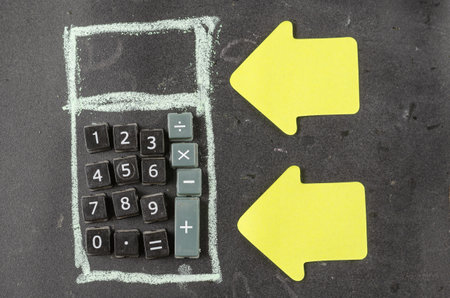 Business, Finance Concept. Yellow paper bookmarks and a Calculator drawn on a chalkboard. Hand-drawn calculator shape with plastic buttons. Top view. Selective focus.の写真素材