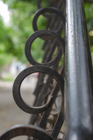 Defocused shot of black metal railing with decorative elements. Metallic repeating curled bars. Fencing of the exterior entrance to the building.の写真素材