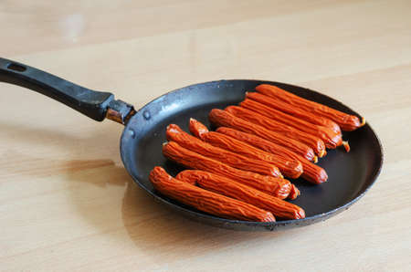 A pan of hunting sausages on a beige table. A portion of ready-to-eat food. Fried sausages. Selective focus.の写真素材