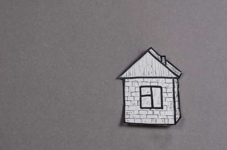 A paper figure of a painted house against a gray background. Hand-drawn single-story building under a corner roof. Minimalism. Top view. Copy spaceの写真素材