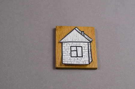 Minimalist composition with a paper figure of a painted house and a wooden dock against a gray background. Hand-drawn One-story building with window and door. Property. Top view. Copy spaceの写真素材