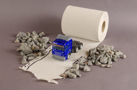 Toy truck rides along the road among the rocks. The road is made from a roll of toilet paper. Selective Focus.の写真素材