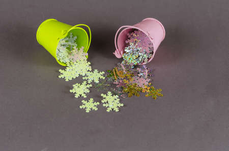 Multicolored sparkles fall out of buckets on a gray background. Green and pink metallic verdro. Selective focus.の写真素材