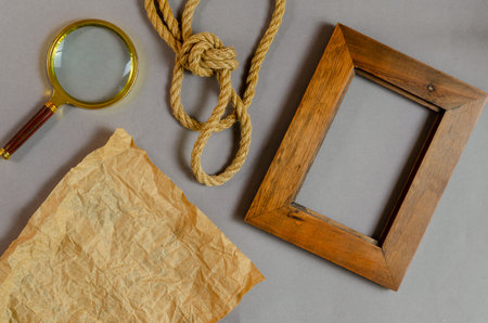 Empty photo frame and rope against a gray background. Wooden picture frame. Magnifying glass....