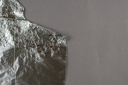 Crumpled foil against a gray background. Roll of aluminum foil for food packaging with an uneven torn edge. Food packaging. Top view. Copy space.の写真素材