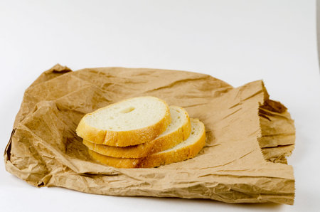 Slices of bread in a paper bag. Three slices of wheat bread in a brown lunch bag. White background.