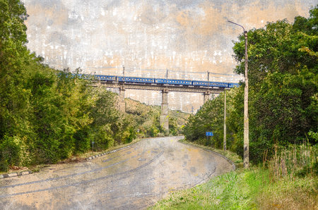Road in the mountains with a railway bridge on top. The train passes over the bridge. Winding road...