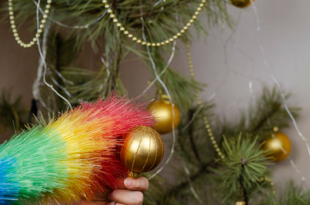 A woman cleans the dust off the Christmas tree balls. An adult woman cleans the gold orbs with a...