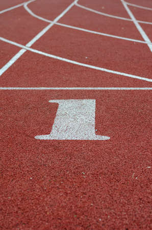 Number 1 on the start line for running. Red jogging tracks at the stadium. Sports, active lifestyle. Selective focus.の写真素材