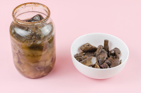 Botulism, food poisoning from canned foods concept. Glass jar and white bowl of homemade pickled...