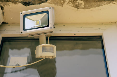 Motion sensor and LED spotlight on the wall of the building. Automatic building perimeter lighting...